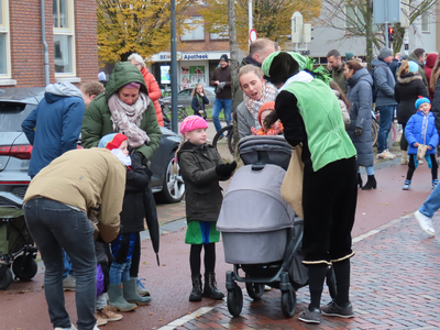 912288 Afbeelding van een Piet, een assistent van Sinterklaas, die strooigoed uitdeelt aan kinderen op de Meerndijk te ...